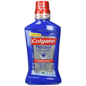 Blue plastic bottle of colgate peroxyl mouth sore rinse with a red cap and silver band, labeled as alcohol-free mild mint.
