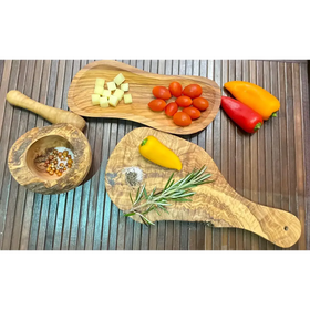 Two olive wood cutting boards, one holding diced cheese and cherry tomatoes while the other displays a yellow pepper, rosemary sprig, and salt.