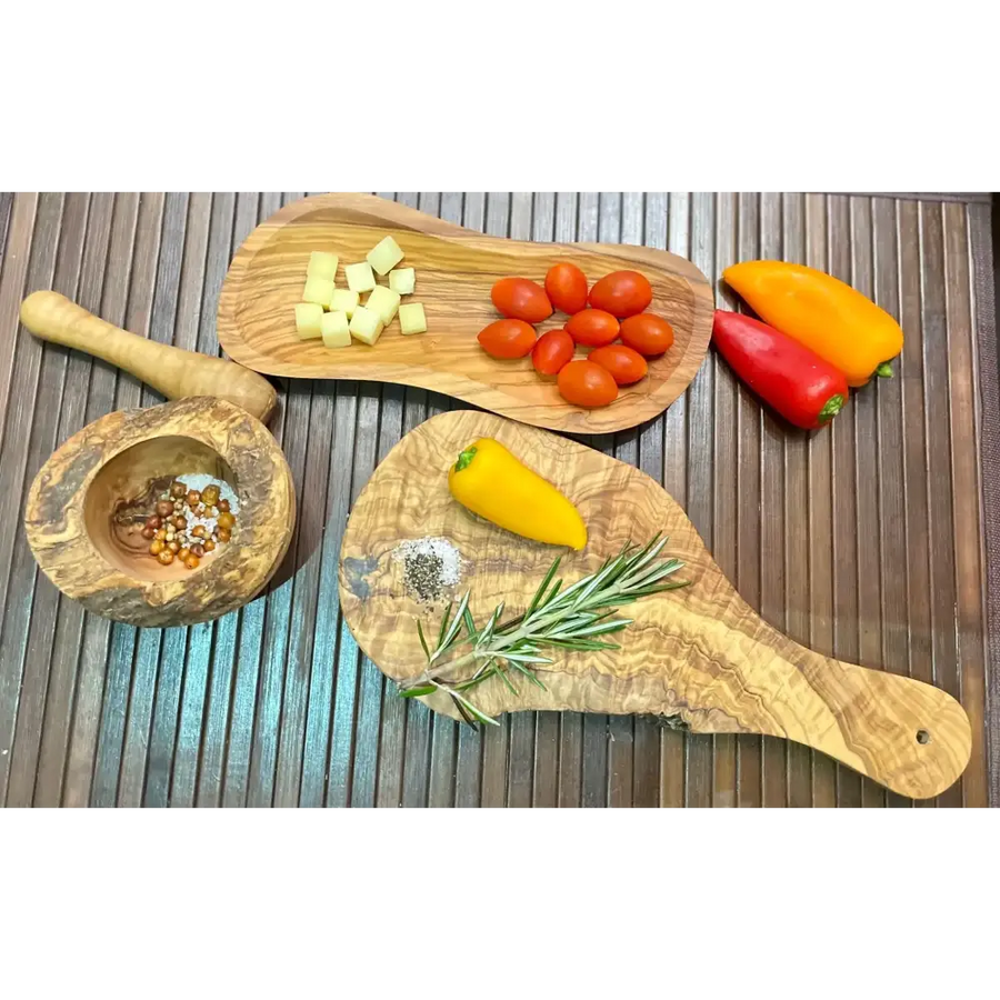 Two olive wood cutting boards, one holding diced cheese and cherry tomatoes while the other displays a yellow pepper, rosemary sprig, and salt.