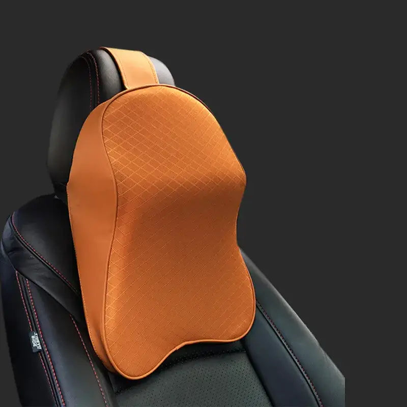 Orange quilted memory foam car headrest pillow with a contoured shape and black leather straps.