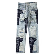 Light-wash denim jeans featuring distressed, ripped patches with black fabric overlays and white line drawings of crucified figures.