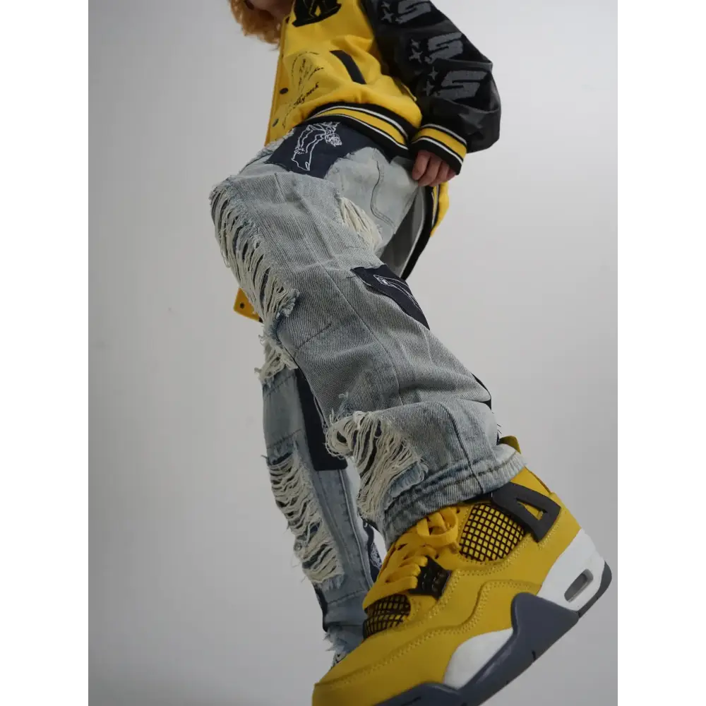 Distressed light-wash denim jeans with frayed edges and black patchwork accents.