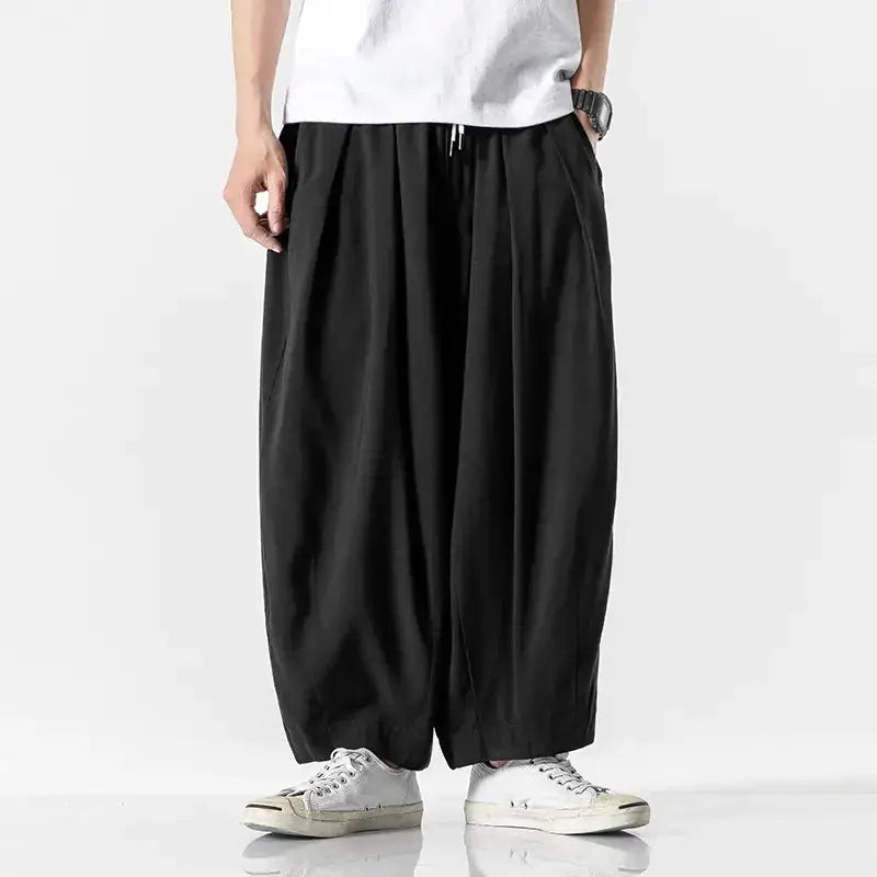 Black, loose-fitting pants with a drawstring waist and wide legs.