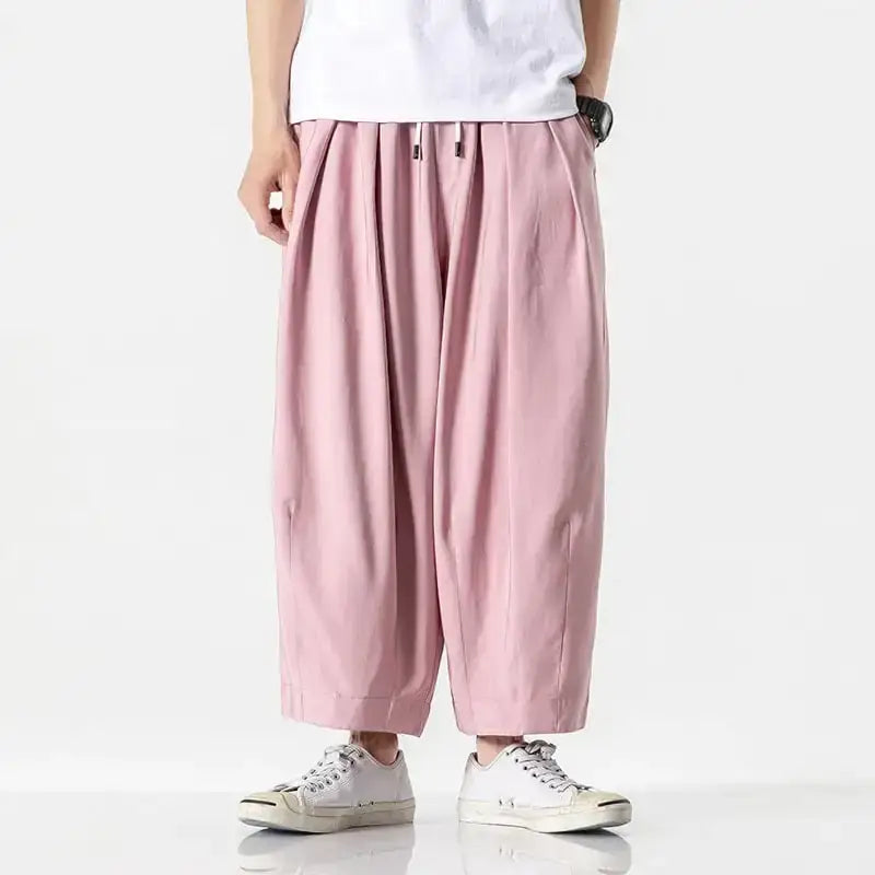 Soft pink, loose-fitting cotton trousers with a drawstring waist and wide legs.
