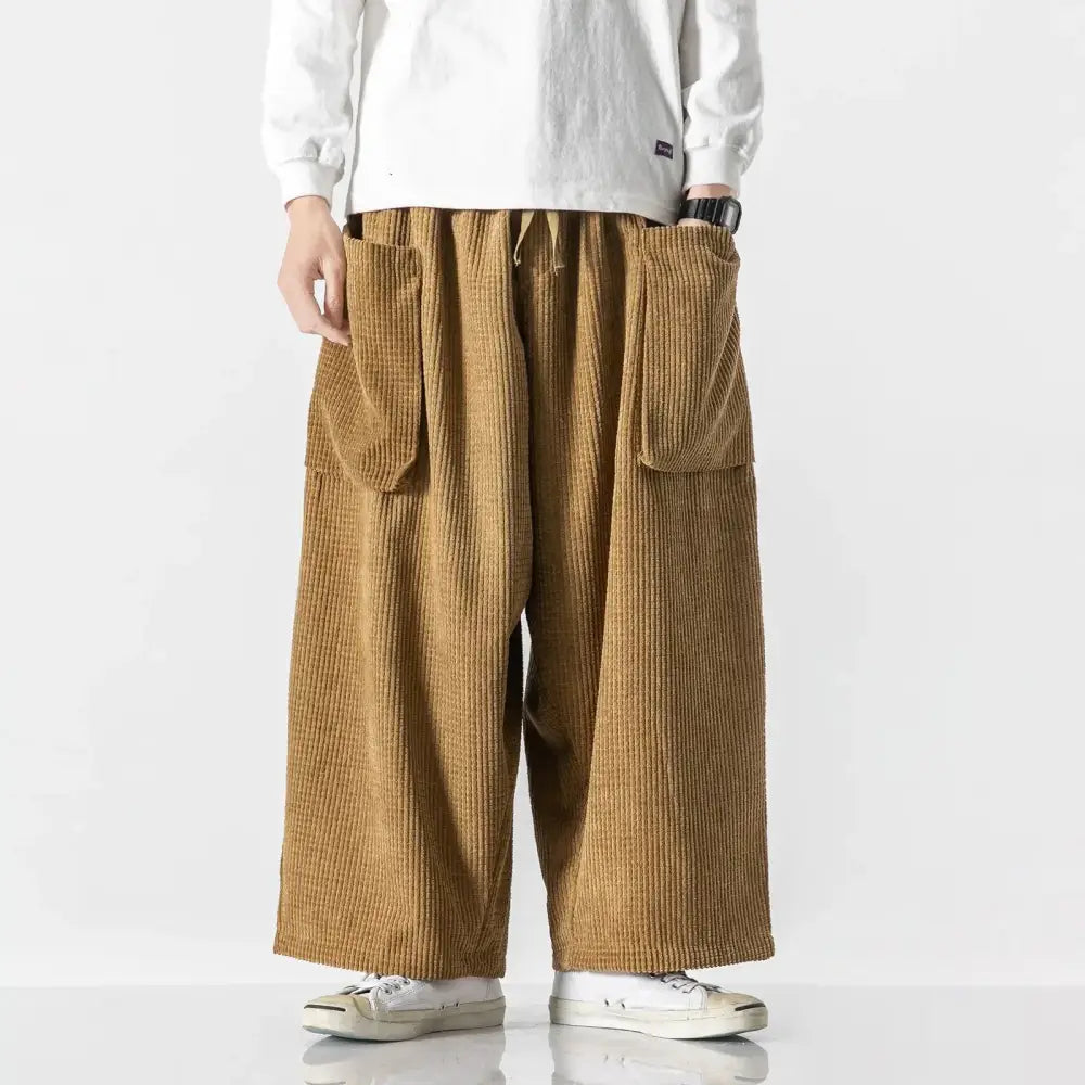 Tan corduroy wide-leg pants with prominent vertical ribs and large side pockets.
