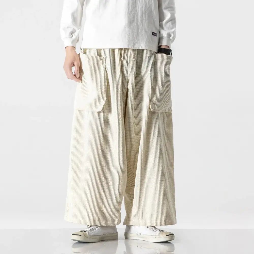 Cream-colored corduroy pants with a relaxed, wide-leg cut and large patch pockets.