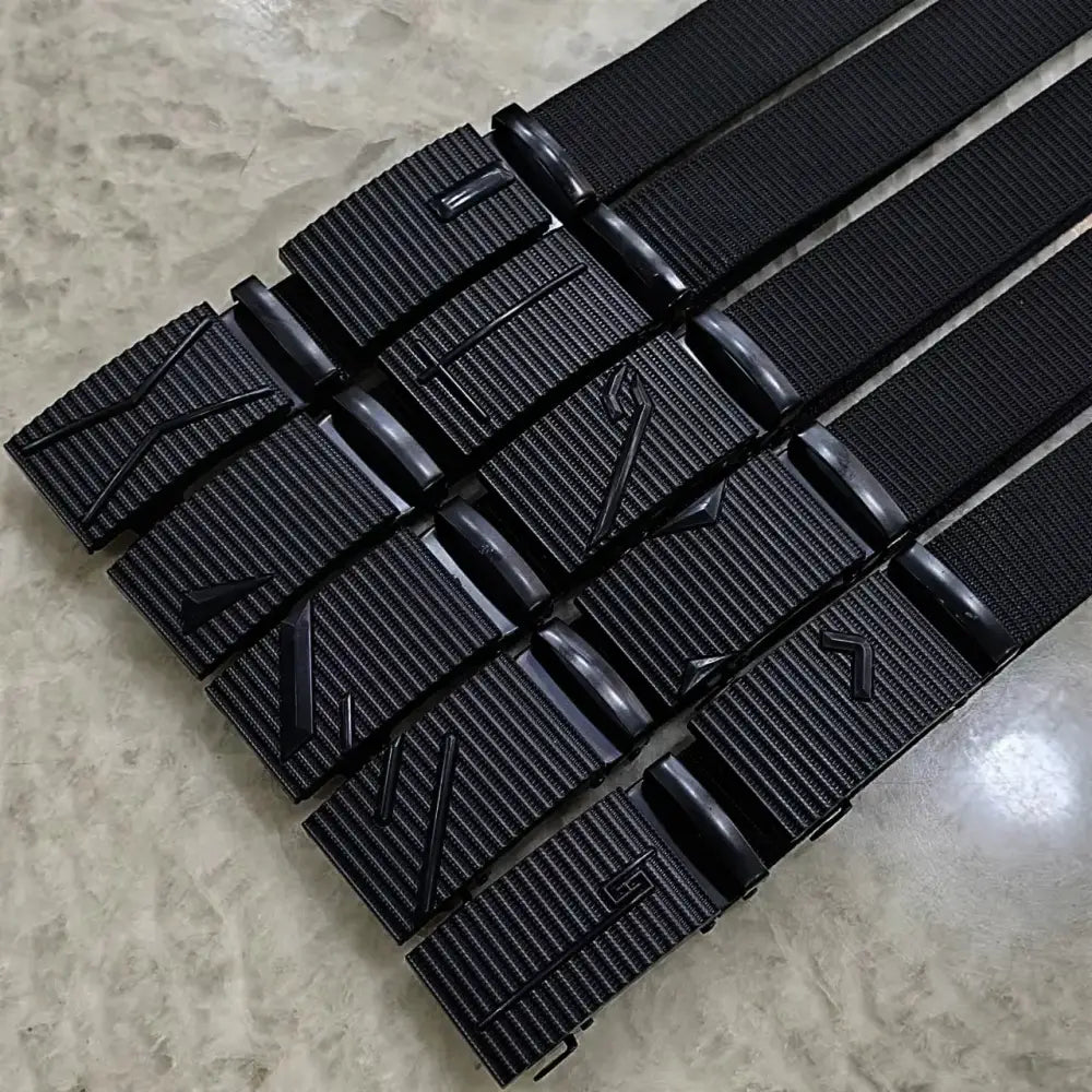 Black tactical-style belts with textured nylon straps and matte black plastic buckles featuring angular, geometric designs.