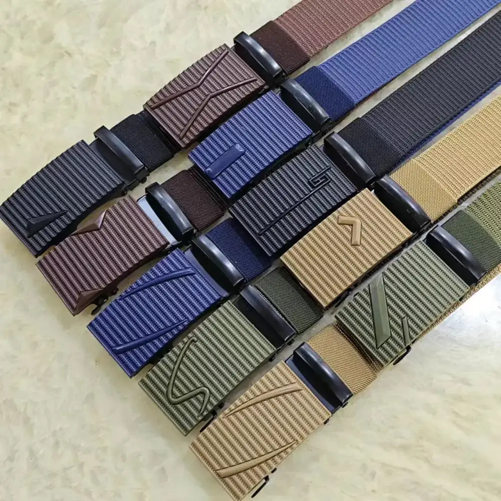 A collection of tactical-style belts in various colors including brown, blue, black, tan, and olive green, each featuring a textured woven fabric strap with a matching plastic buckle that has an embossed logo.