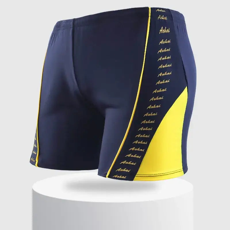 Navy blue swim trunks with bold yellow side panels and a repeating ’aohai’ logo in gold lettering along the seams.
