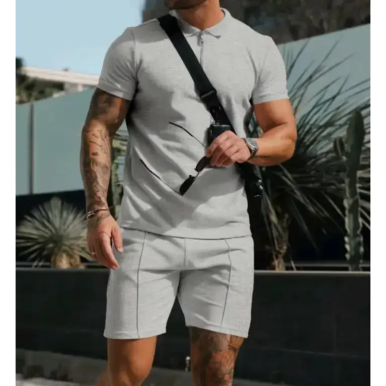 A man wearing a light gray, short-sleeved polo shirt with subtle vertical stripes and matching shorts.