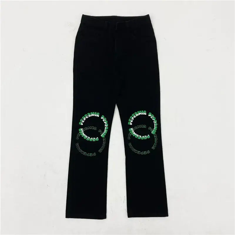 Black pants featuring green and white embroidered text in circular patterns on each knee.