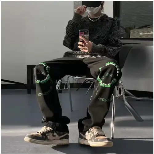 Black joggers with green circular embroidery on the knees and legs