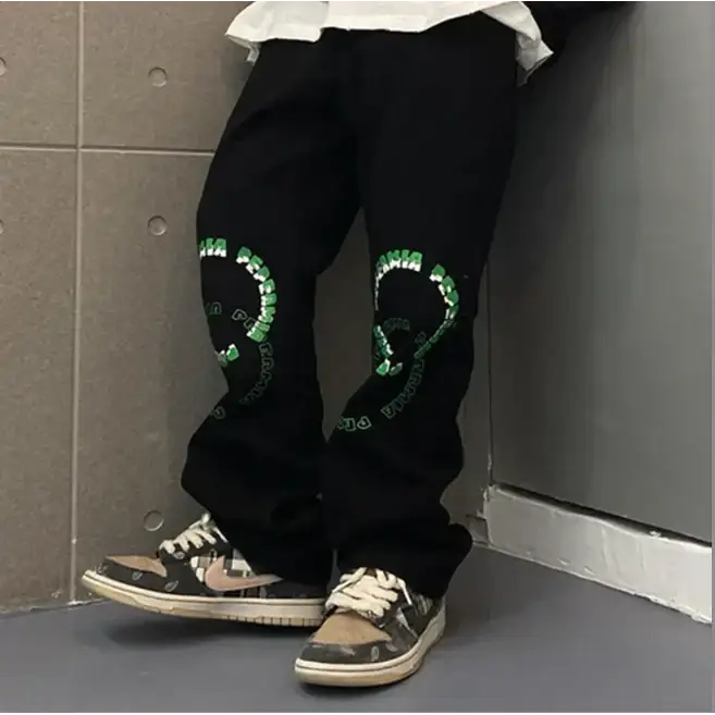 Black tapered pants featuring bold green circular graphics with text on each knee.