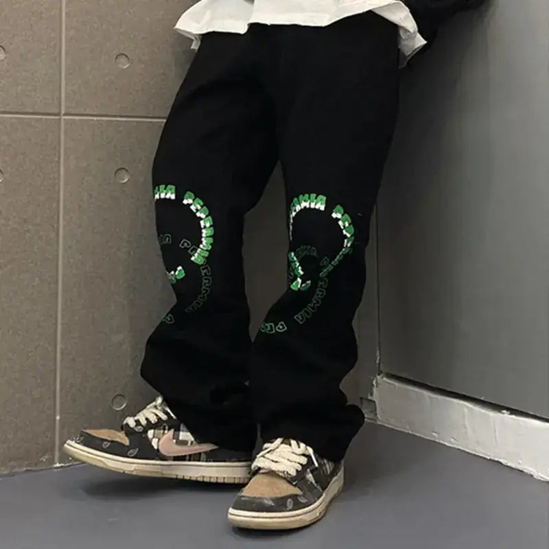 Black tapered pants featuring bold green circular embroidery with text along the outer thigh.