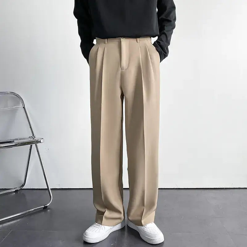 Beige pleated trousers with a smooth, tailored fabric and classic front pockets.