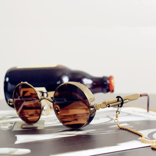 Round, amber-tinted lenses with a brass-colored metal frame and spring-loaded hinges.