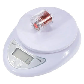 White digital kitchen scale with a clear plastic container filled with red glitter resting on its platform.