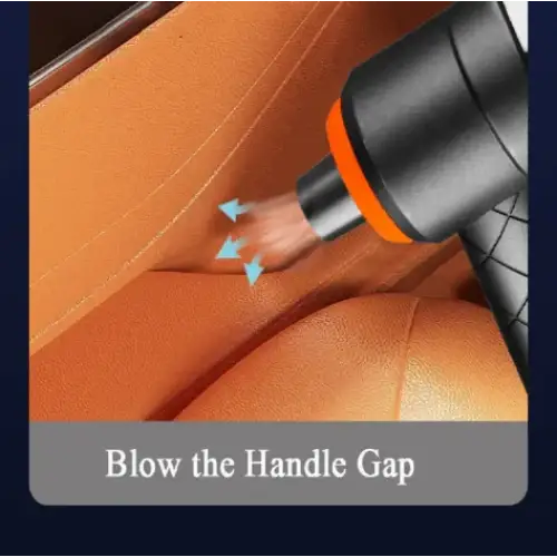 Black and orange handheld vacuum cleaner nozzle being used to blow air into the handle gap of an orange leather car seat.