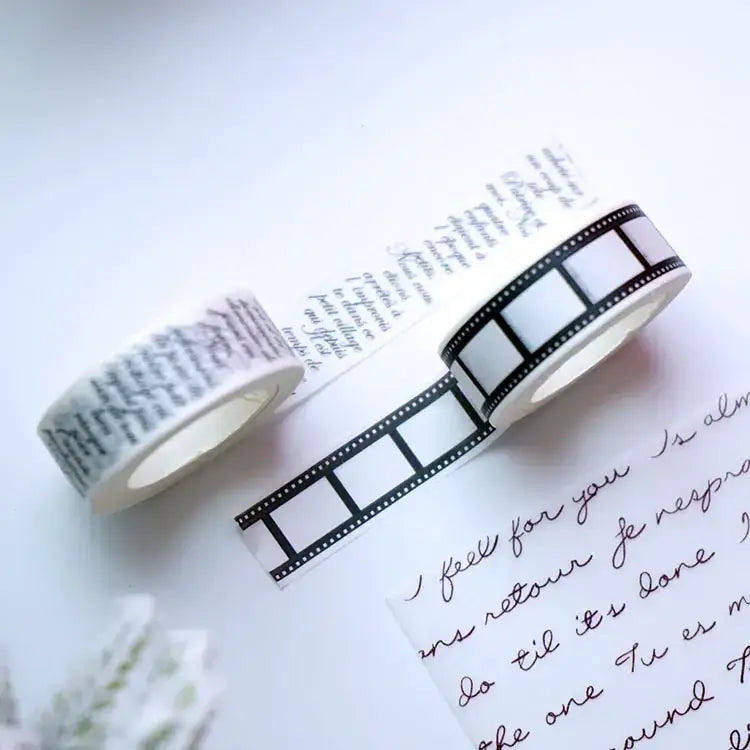 Two rolls of washi tape, one featuring black film strip design and the other with elegant cursive script in dark ink on a light background.