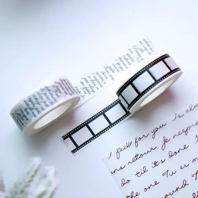 Two rolls of washi tape, one featuring black film strip design and the other with elegant cursive script in dark ink on a light background.