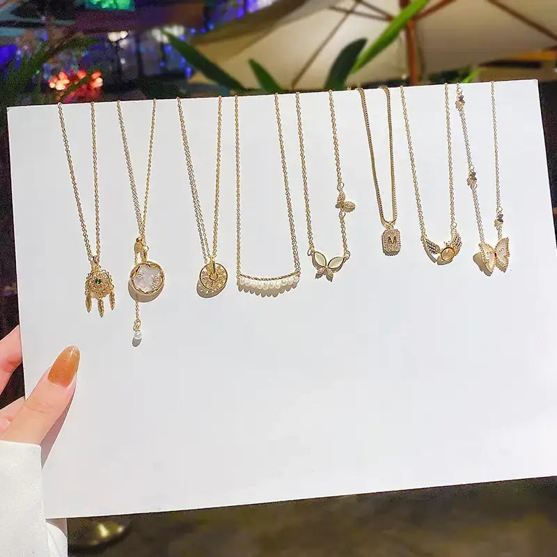 A collection of delicate gold-toned necklaces featuring various charms including a dreamcatcher, pearl accents, and butterfly designs.