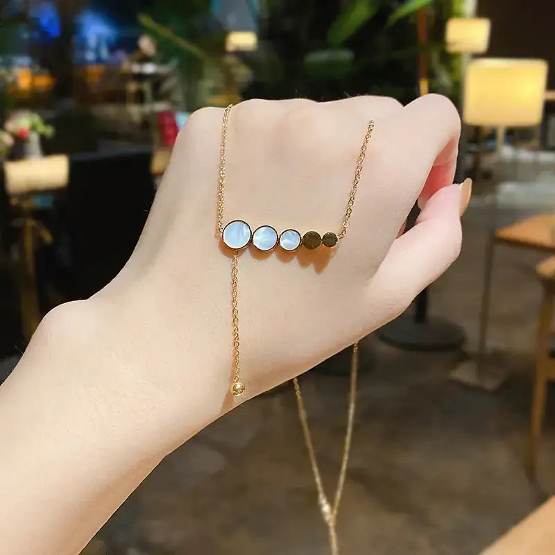 Gold-toned necklace featuring a row of five circular beads—three with iridescent mother-of-pearl and two solid gold—that dangles elegantly from a delicate chain.