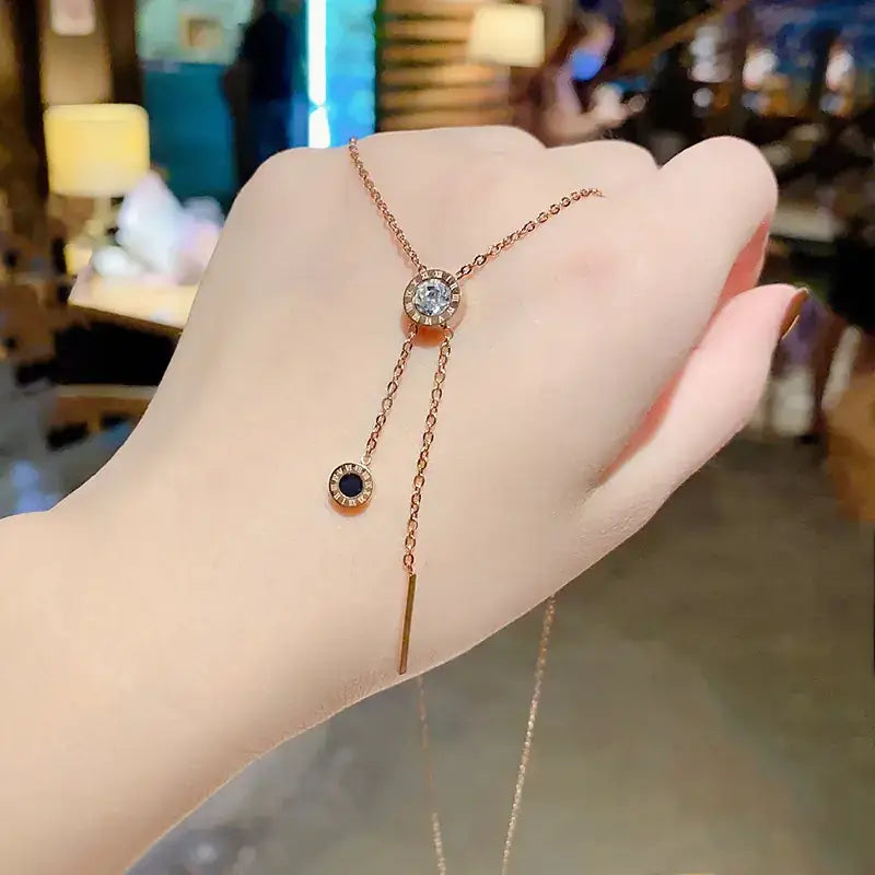 A delicate rose gold y-shaped necklace featuring a central round diamond accent and dangling elements with black onyx stones, suspended from fine chains.