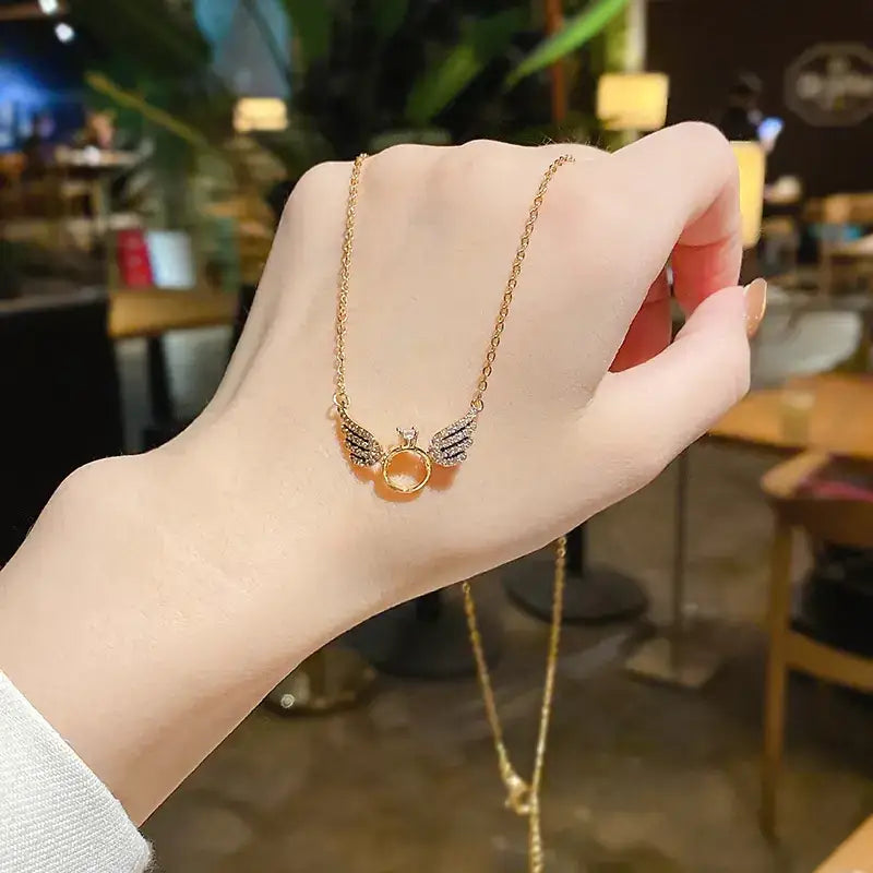 A delicate gold-toned necklace featuring a central amber-colored gemstone flanked by sparkling wing-shaped charms.