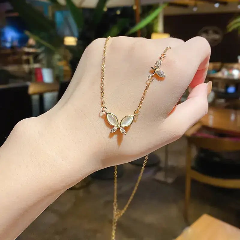 A delicate gold chain bracelet featuring a butterfly pendant with mother-of-pearl wings and sparkling crystal accents.
