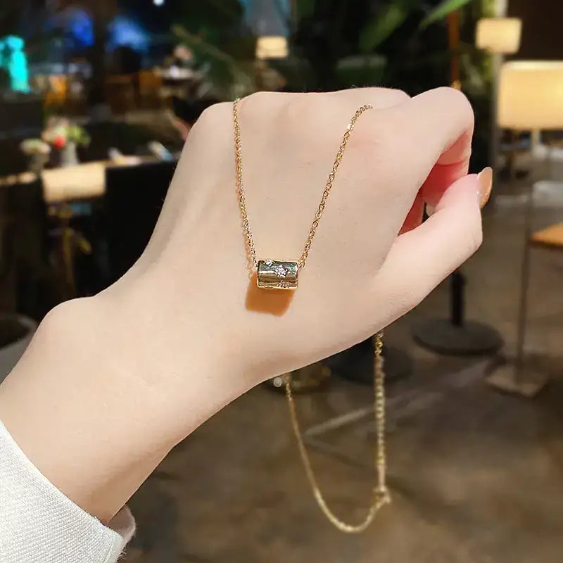 Gold-toned necklace with a rectangular, gemstone-encrusted pendant.