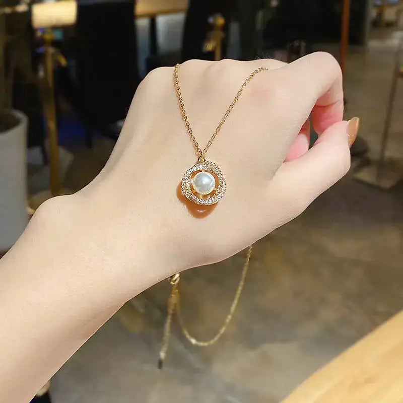 A delicate gold necklace featuring a central pearl encircled by sparkling diamonds, suspended from an elegant chain.