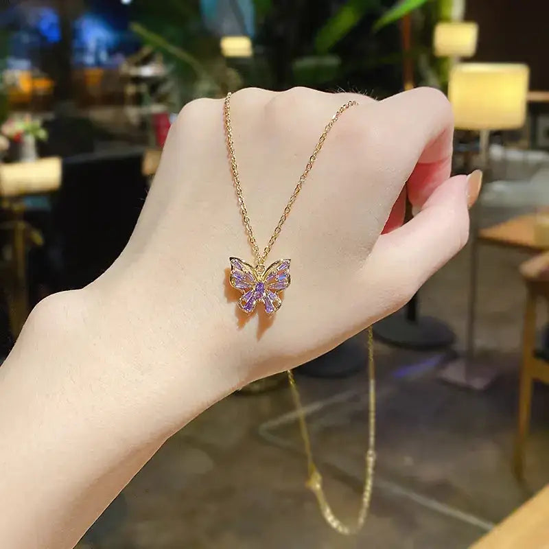 A delicate gold chain necklace featuring a butterfly pendant adorned with sparkling purple crystals.