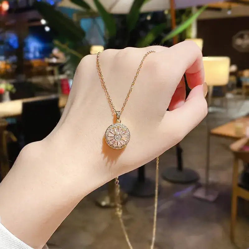 A delicate rose gold necklace featuring a round, sunburst-style pendant adorned with sparkling clear stones.