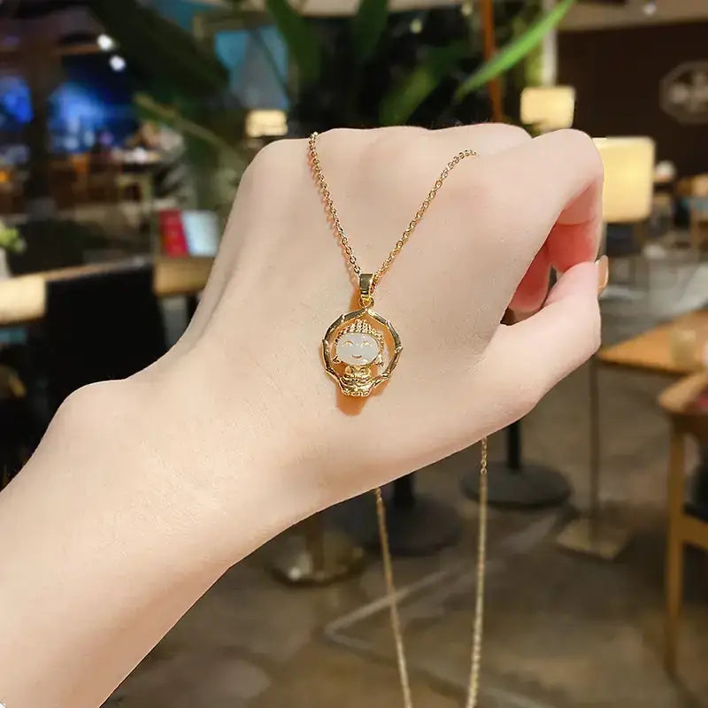 Gold-toned necklace featuring a circular pendant with an intricately detailed buddha face set in a delicate, ornate frame.