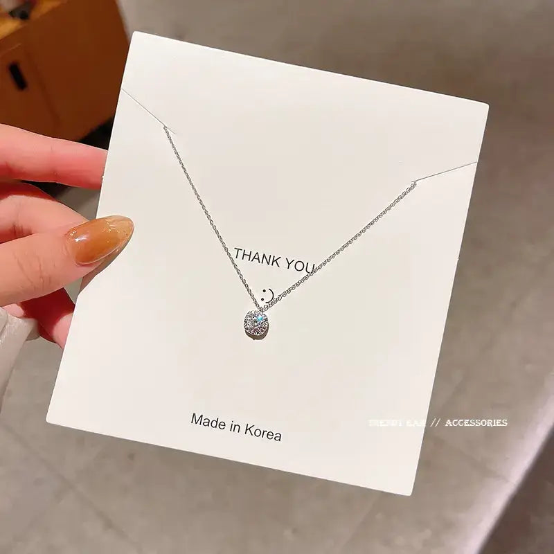 A delicate silver chain necklace featuring a round, sparkling pendant with embedded crystals.
