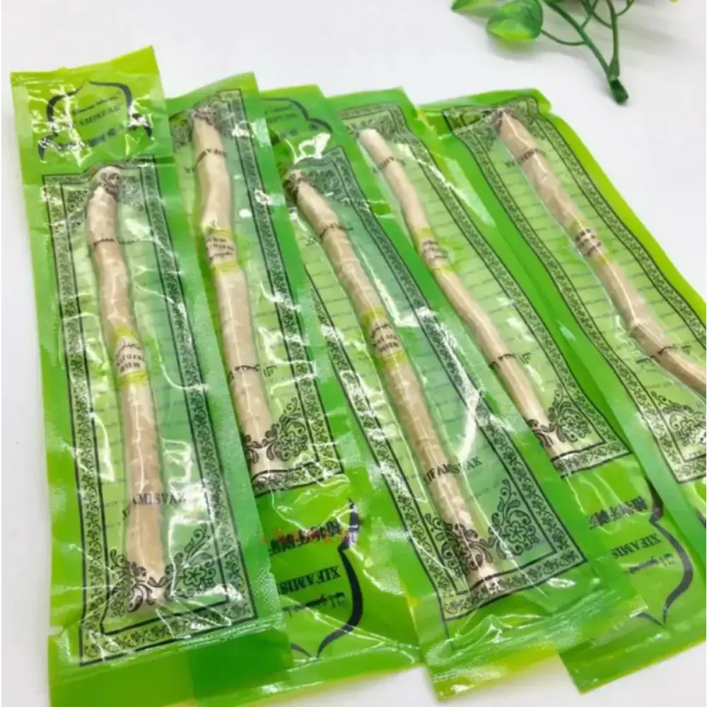 Five individually packaged licorice root sticks, each encased in vibrant green plastic wrap with decorative black and white patterns.