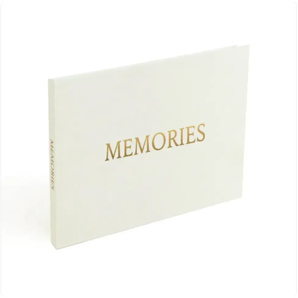 A cream-colored memory book with gold foil lettering that reads ’memories’ on the cover.