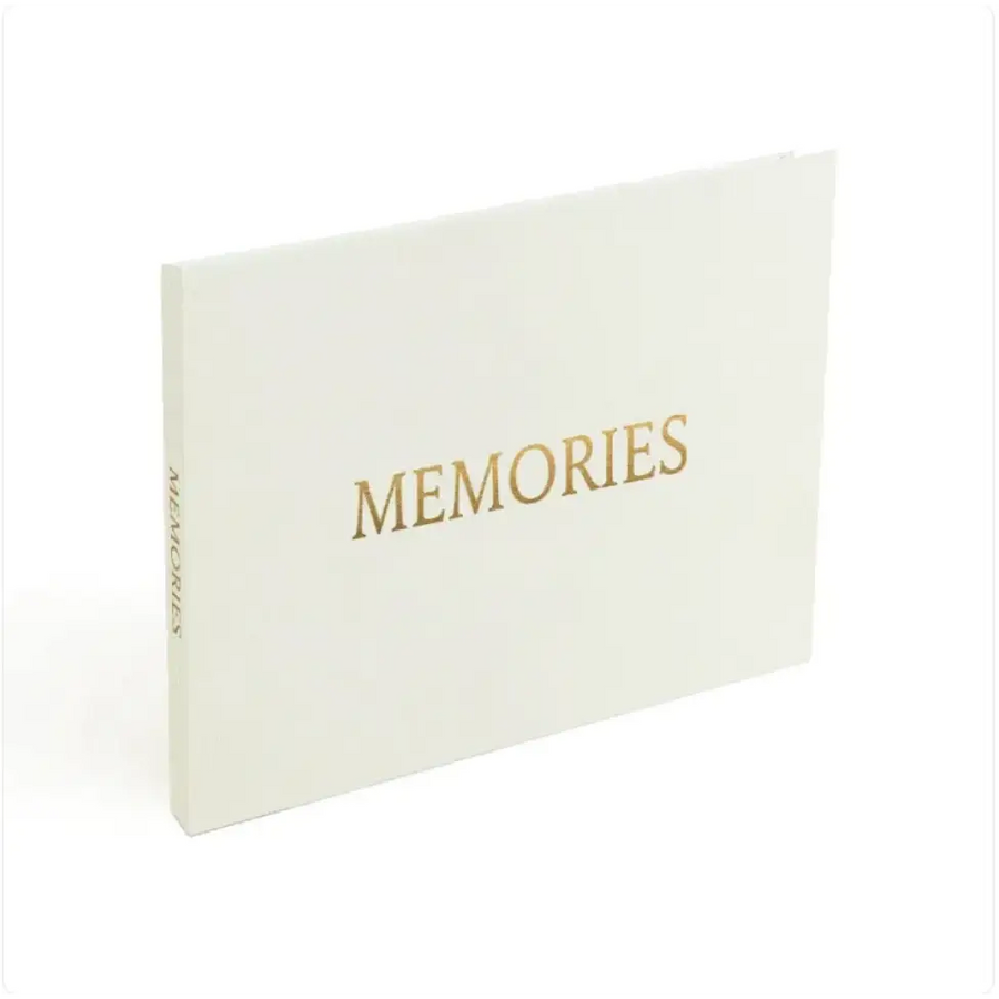 A cream-colored memory book with gold foil lettering that reads ’memories’ on the cover.