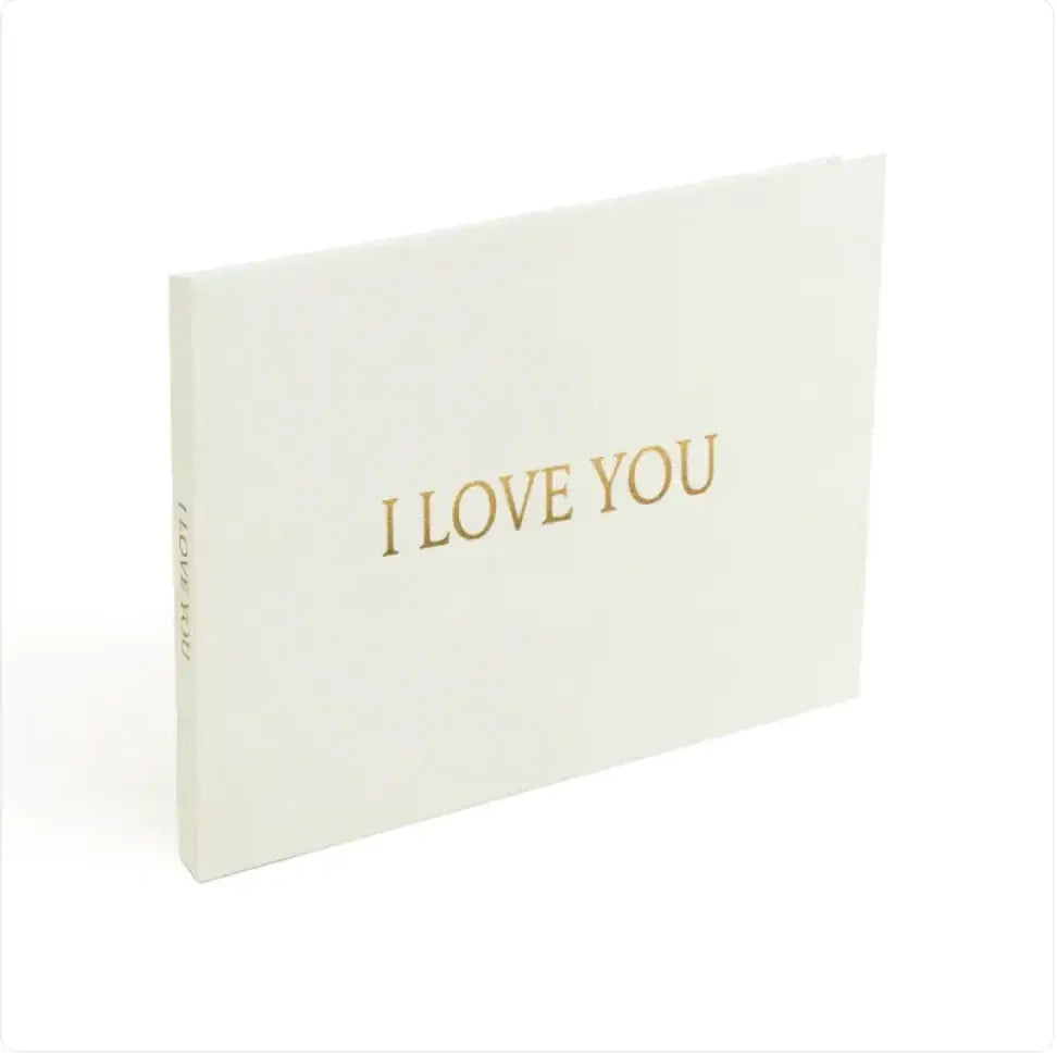 A minimalist white card with elegant gold foil lettering that reads ’i love you.’