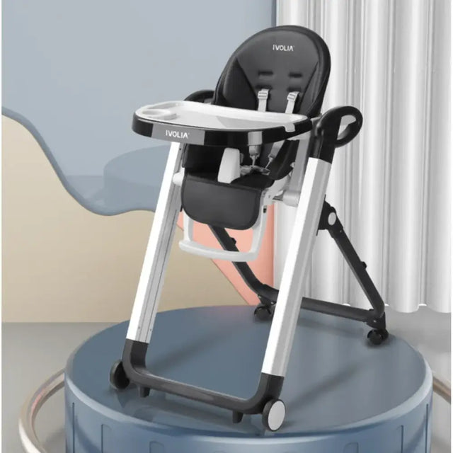 Black and silver ivolia brand baby high chair with a tray, adjustable seat, and wheels.