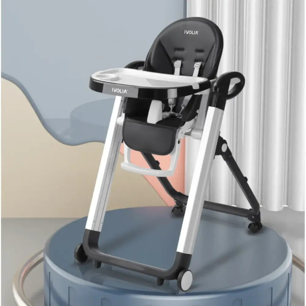 Black and silver ivolia brand baby high chair with a tray, adjustable seat, and wheels.