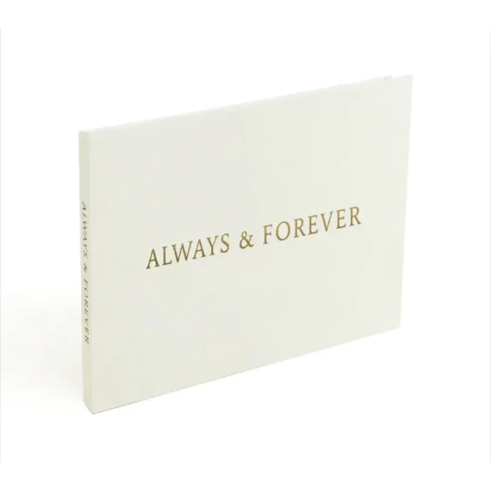 A minimalist white photo album with gold foil lettering that reads ’always & forever’ on the cover.