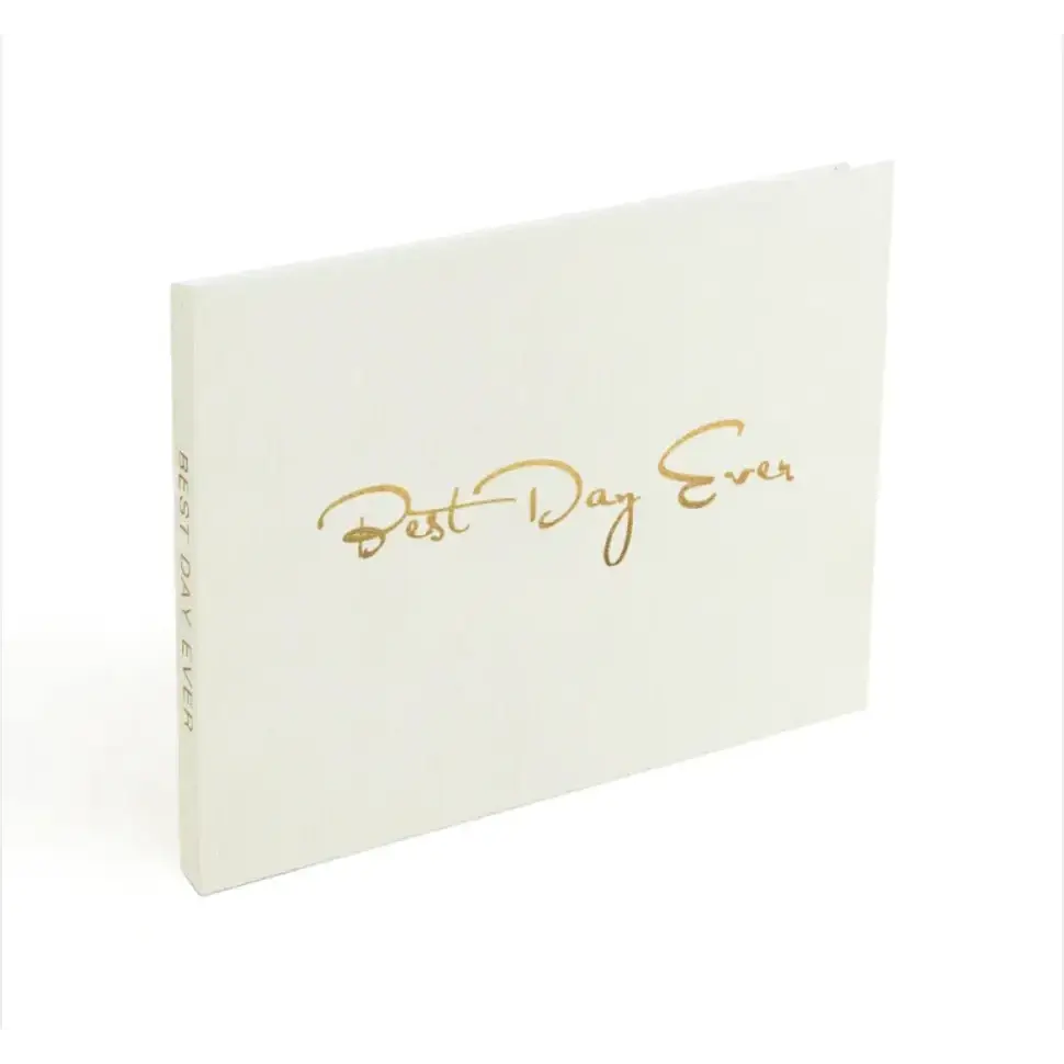 A white hardcover journal with gold foil lettering that reads ’best day ever.’
