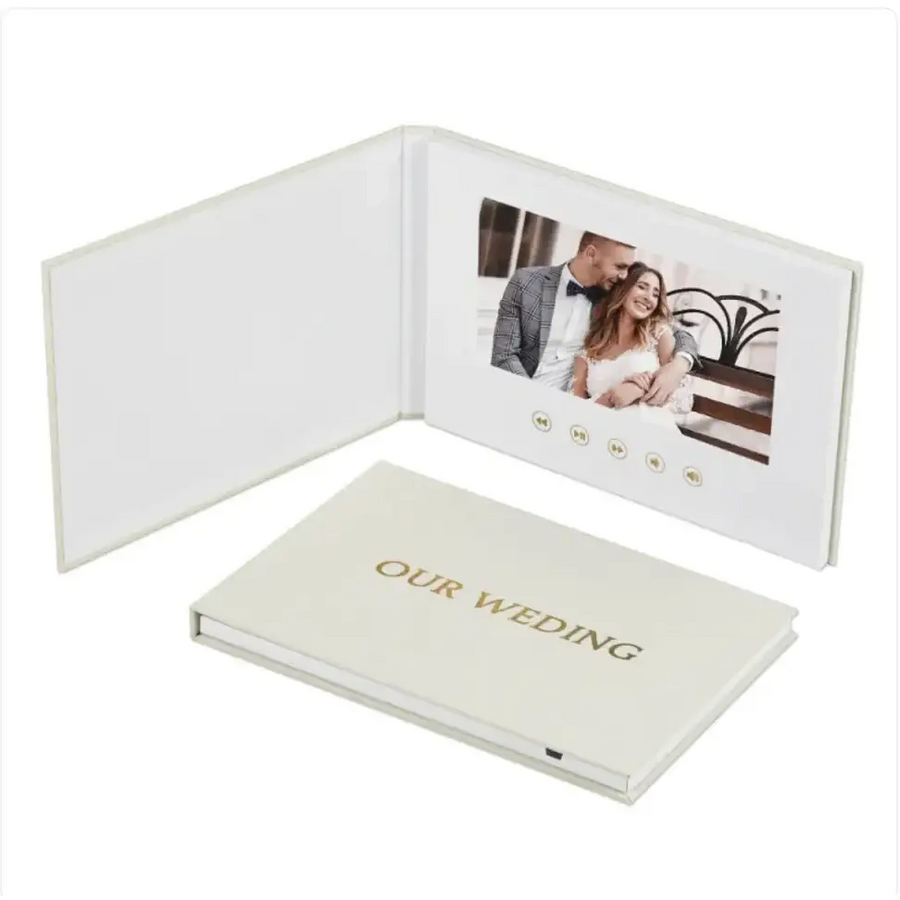 Cream-colored digital photo book with gold foil ’our wedding’ embossing and a built-in screen displaying a couple’s wedding photo.