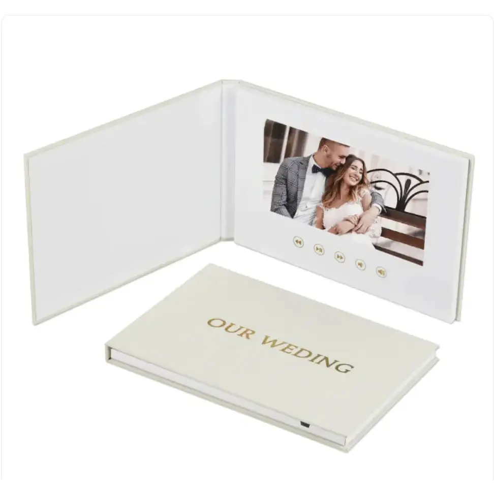 Cream-colored digital photo book with gold foil ’our wedding’ embossed on the cover and a built-in screen displaying a couple’s wedding photo.