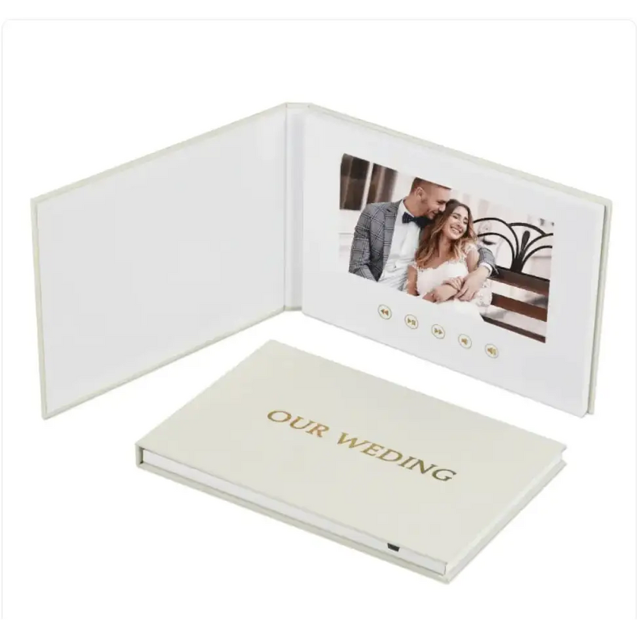 Cream-colored digital photo book with gold foil ’our wedding’ embossed on the cover and a built-in screen displaying a couple’s wedding photo.