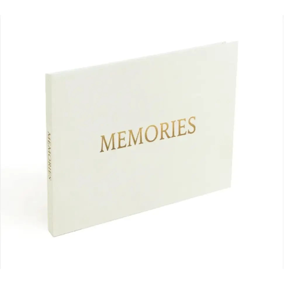 A cream-colored memory book with gold foil lettering that reads ’memories’ on the cover.