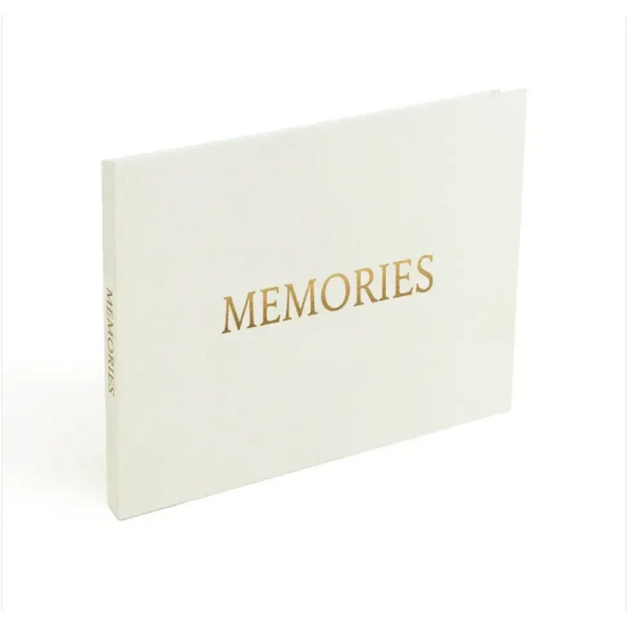 A sleek white memory book with elegant gold foil lettering spelling ’memories’ on the cover.