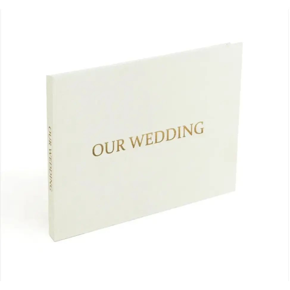 A minimalist white wedding album with elegant gold foil lettering that reads ’our wedding’ on the cover.
