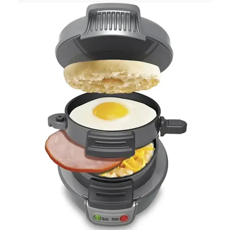 Gray electric breakfast sandwich maker with a fried egg, ham slice, and cheese inside.